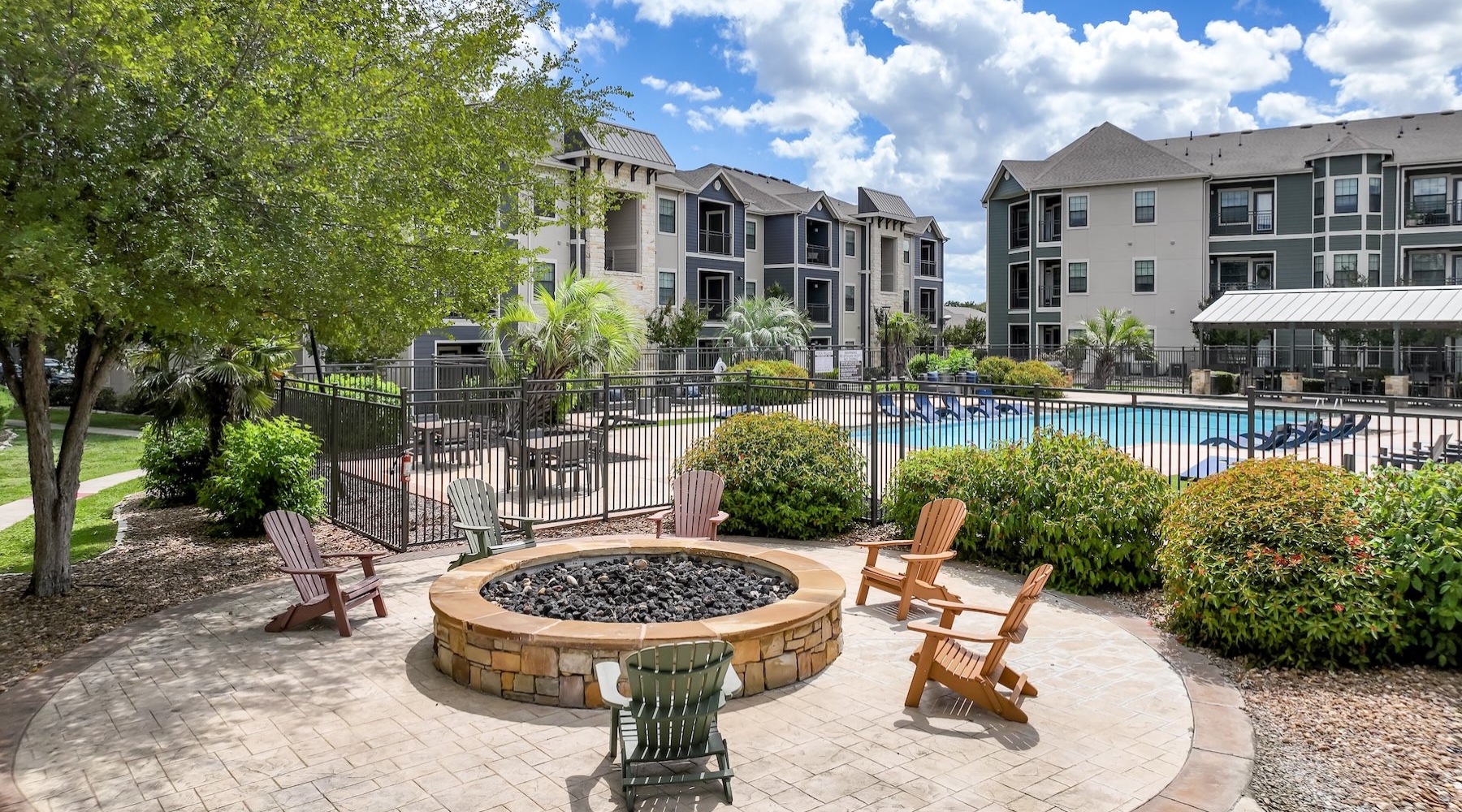 gated resort style pool with a fire pit with chairs close by