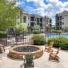 gated resort style pool with a fire pit with chairs close by